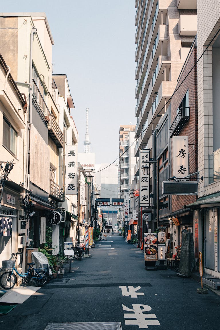 A lively street in Tokyo with signs, bikes, and a view of Tokyo Skytree in the distance.